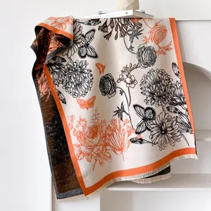 Detail of floral and butterfly print scarf with orange borders and long fringe tassels