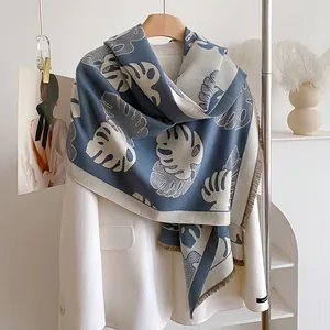 Détail de l'écharpe tricotée à motif de feuilles et franges sur un blazer blanc