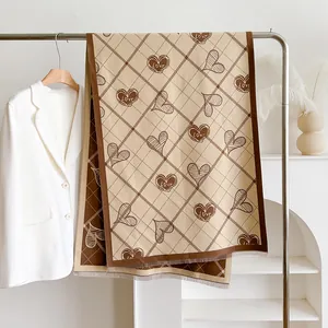 Dettaglio della sciarpa in finto cashmere con stampe a cuore e bordi con frange