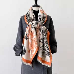 Detail of floral and butterfly print cashmere scarf with orange borders and fringe edges