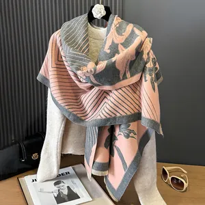 Dettaglio del motivo a camelia e delle frange sullo scialle in cashmere rosa e grigio