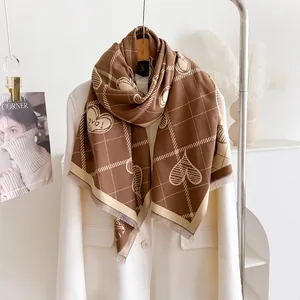 Dettaglio di sciarpa a quadri marroni con cuori disegnati e bordi a frange morbide
