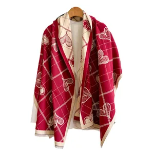 Sciarpa rossa effetto cashmere con cuori bianchi e frange su una gruccia