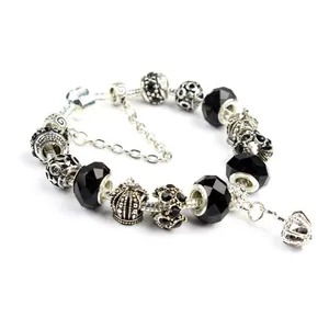 Macro view of silver snake chain bracelet with crown pendant and black crystal charms