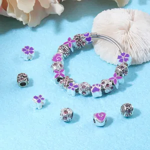 Vue détaillée des breloques fleurs en émail violet et perles sur bracelet chaîne argentée