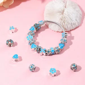 Détail de perles cœur en cristal bleu et ensemble de bracelet chaîne serpent sur fond rose
