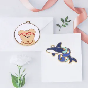 Vue détaillée des breloques émaillées ours et dauphin avec bordure dorée pour bijoux