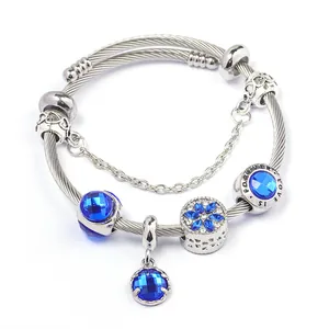 Dettaglio di un bracciale in acciaio argento con perline di cristallo blu e ciondoli a cuore