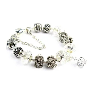 Detail of silver snake chain bracelet featuring turquoise beads and crown pendant