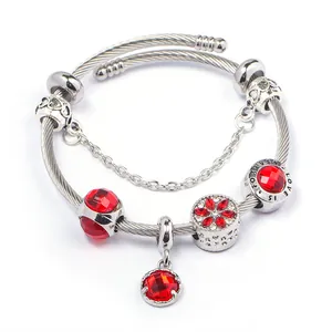 Dettaglio macro del bracciale con ciondoli in acciaio inossidabile e cristalli rossi