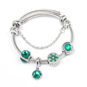 Dettaglio del bracciale a cavo argento con ciondoli in cristallo verde e incisione Love Is Forever
