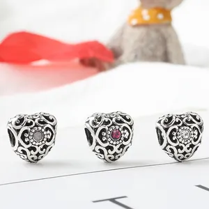 Macro shot of three vintage hollow heart beads with inset grey, pink, and white crystals