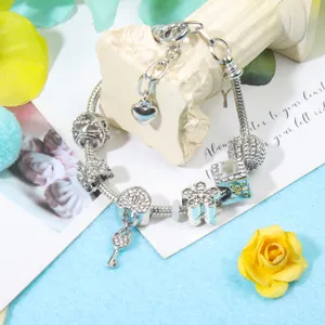 Vista detallada de la pulsera con dijes plateados con colgantes de corazón, llave y flor