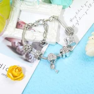 Detalle de pulsera DIY con colgante de llave de corazón y cuentas de flores blancas