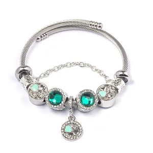 Detailed close-up of clover beaded steel bracelet with green gemstones and heart charms