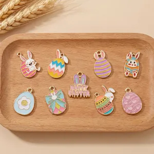 Detalle de dijes esmaltados de Pascua con conejos y huevos sobre bandeja de madera