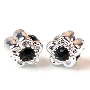 Gros plan de boucles d'oreilles fleur argentée avec cristal noir et cinq pétales
