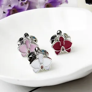 Detalle de dijes de flores de orquídea esmaltadas con circonita rosa para joyería