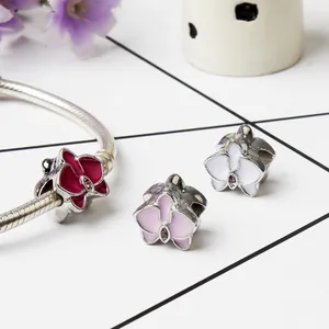 Detalle de dijes de orquídeas en esmalte de colores con pulsera de cadena de plata