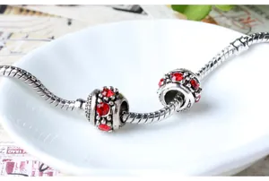 Detalle de pulsera de cadena de serpiente de plata con dos dijes redondos de pedrería