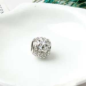 Makroaufnahme der silbernen Schneeflocken-Charm mit Kristallen auf einer Keramikschale