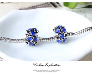 Gros plan sur bracelet chaîne serpent argenté avec charms en cristal bleu sur porcelaine