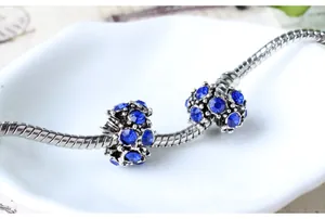 Macro de perles à gros trous en cristal bleu sur chaînes serpent argentées sur céramique