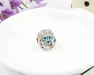 Vue macro d'une perle argentée avec poisson en émail bleu pour bracelets DIY