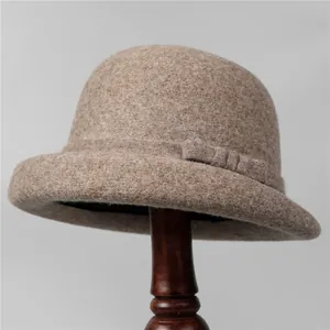 Elegant khaki wool felt cloche hat with a bow detail on a vintage wooden stand