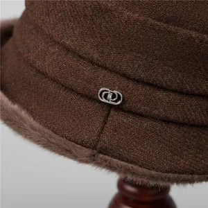Macro di un cappello in tweed marrone per signora con bordo in ecopelliccia e fibbia in metallo