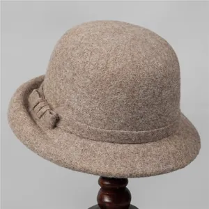 Close-up of wool felt cloche hat with ribbon bow detail on a wooden stand
