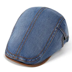 Detailed view of denim flat cap with orange stitching and brown leather brim trim