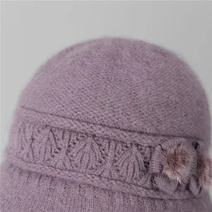 Detalle del gorro de punto de piel de conejo violeta oscuro con textura suave y una flor