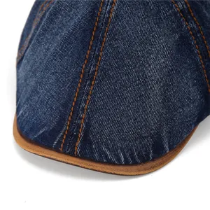 Close-up of vintage denim beret with orange stitching and brown trim details