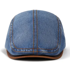 Detail of vintage denim cap with brown leather brim and contrast orange stitching
