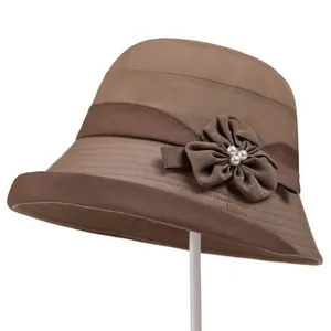 Detail of dark brown cloche hat featuring a fabric flower and white faux pearls