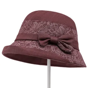 Detailed close-up of dark red cotton linen sun hat with floral band and bow decoration