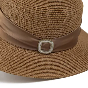Elegant brown woven flat top straw hat featuring a silk ribbon and pearl metal buckle