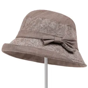Detail of elderly women's sun hat featuring brown fabric with leaf pattern ribbon bow