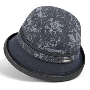 Detail of navy blue sun hat featuring gray floral print and elegant metal brand emblem