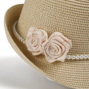 Detail of elegant straw hat featuring fabric roses and delicate white pearl trim