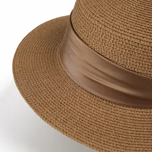 Detailed close-up of dark brown woven straw hat with elegant satin ribbon detail
