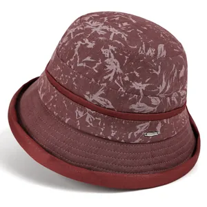 Detail view of burgundy sun hat with floral pattern and metallic emblem for elderly women