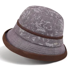 Detail of purple-gray bucket hat with white abstract patterns and silver metal badge