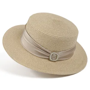 Detailed macro view of woven straw boater hat with champagne satin ribbon and pearl buckle
