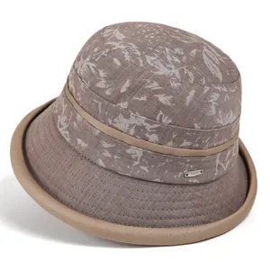 Detail of floral pattern fabric and metal logo on beige summer sun hat for elderly women