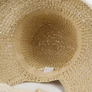 Detail view of beige paper straw hat interior with adjustable drawstring and lace trim