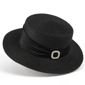 Close-up of black straw boater hat featuring a satin ribbon and pearl buckle ornament