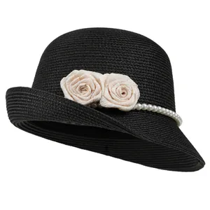 Detail of woven straw texture with white roses and pearl chain on a black cloche hat