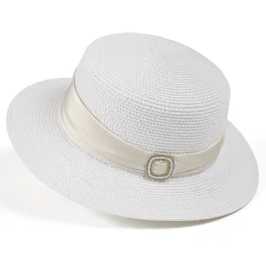 Detail of white straw boater hat featuring elegant satin ribbon and pearl buckle